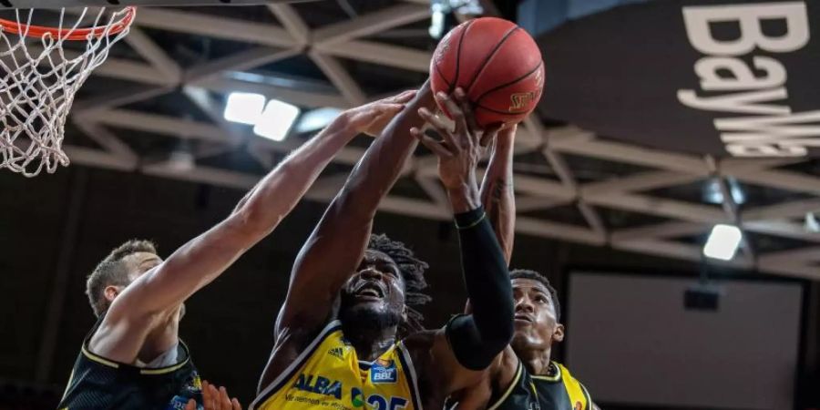 Landry Nnoko (M) von Alba Berlin setzt sich im Vorrundenspiel gegen zwei seiner Gegenspieler durch. Foto: Tilo Wiedensohler/camera4/BBL/pool/dpa