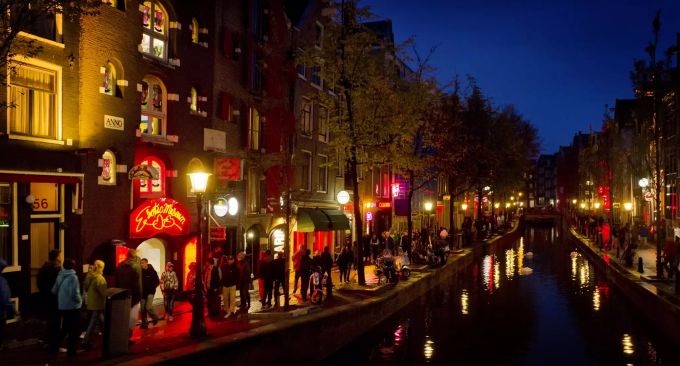 Menschen schlendern am Abend an einer Gracht entlang durch den Rotlichtbezirk De Wallen. (Archivbild) amsterdam coffeeshop