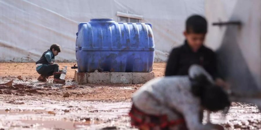 Kinder füllen in einem provisorischen Lager in der Region Idlib Behälter mit Wasser auf. Von den Hilfsgütern, die bisher die Grenzübergänge passierten, sind westlichen Angaben zufolge etwa 2,8 Millionen Menschen abhängig. Foto: Anas Alkharboutli/dpa