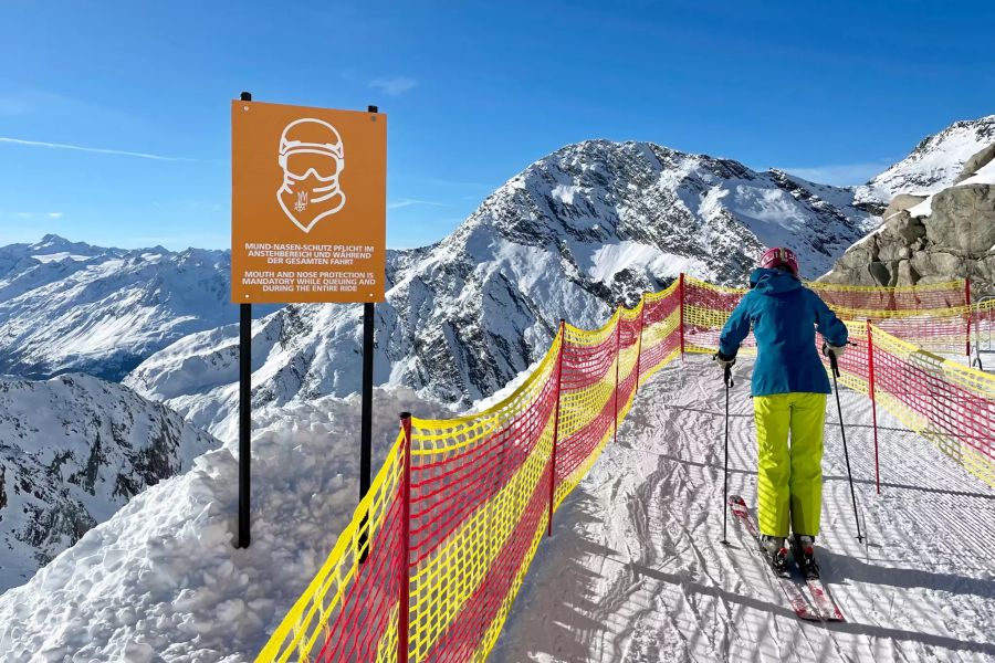 Skipiste, daneben Schild mit Vorgaben für Coronamassnahmen