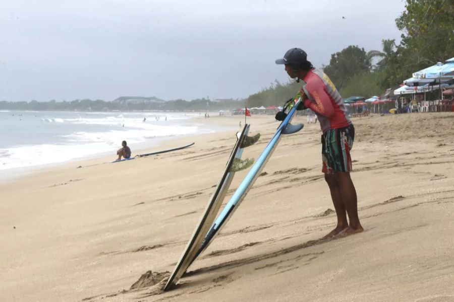 Ein Surf-Lehrer wartet an einem Strand in Bali auf die Touristen.