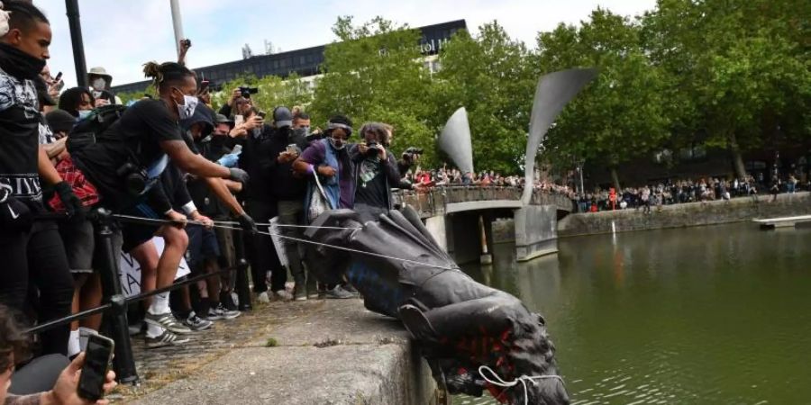 Demonstranten werfen die Statue des Sklavenhändlers Edward Colston in den Hafen von Bristol. Foto: Ben Birchall/PA Wire/dpa