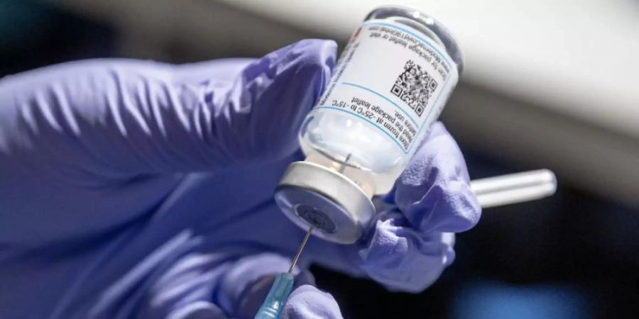 Eine Krankenschwester zieht Corona-Impfstoff aus einer Ampulle in eine Spritze auf. Foto: Markus Scholz/dpa