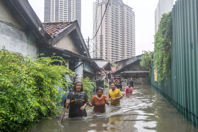Menschen gehen auf einer vom Hochwasser überfluteten Strasse. Unmittelbar nach der Silvesterfeier in der indonesischen Hauptstadt kam es zu schweren Überschwemmungen, welche die Schliessung eines Flughafens zur Folge hatte. Tausende von Einwohnern mussten ihre Häuser verlassen. Überschwemmungen in Indonesien