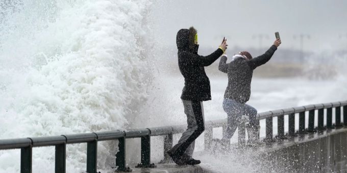 Zwei Personen werden am 2. Februar 2022 in Lynn Shore von einer Welle nass gemacht.