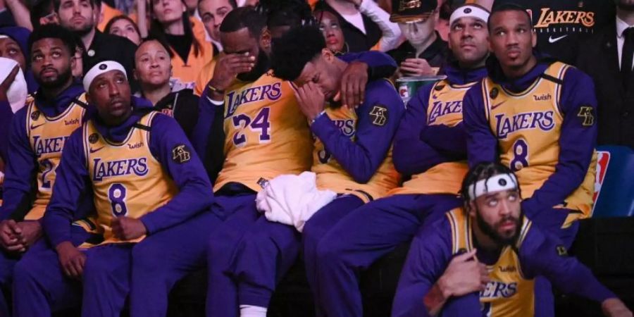 LeBron James (M,l) und Quinn Cook (M,r) von den Los Angeles Lakers schlagen bei einem Video-Beitrag über Kobe Bryant die Hände vors Gesicht. Foto: Kelvin Kuo/AP/dpa