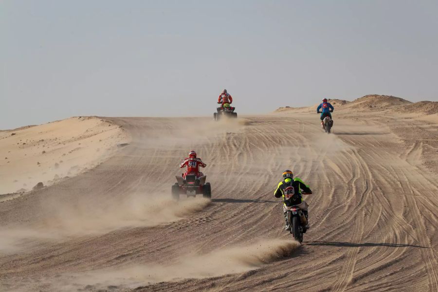 Quads und Motorräder auf einem kleinen Stück Wüstenstrasse.