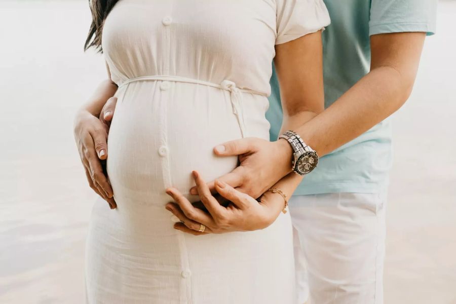 Mann hält den Bauch seiner schwangeren Frau.