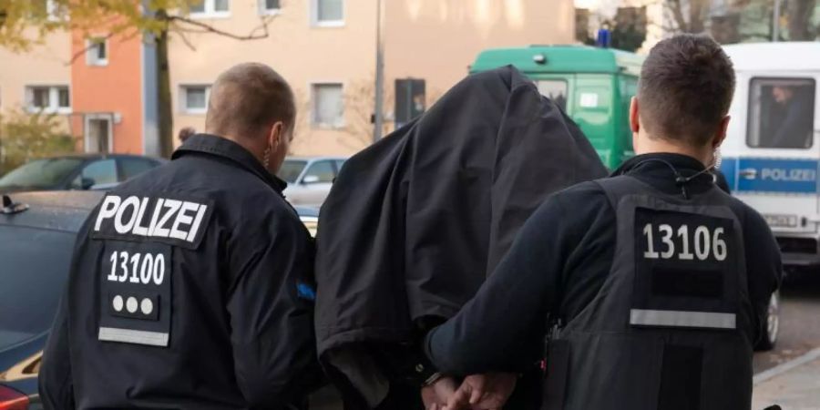 Polizeibeamte führen einen Mann nach einer Razzia in Berlin ab. Der Einsatz richtete sich gegen kriminelle Clan-Mitglieder. Foto: Paul Zinken/dpa/Archiv