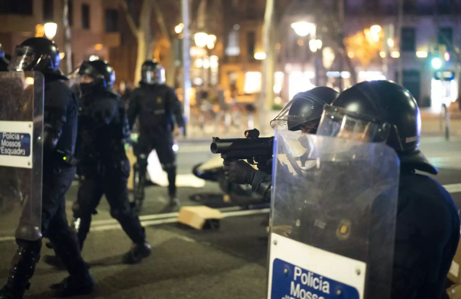 Polizisten zielen mit Gummischrott-Werfer auf die Demonstranten.