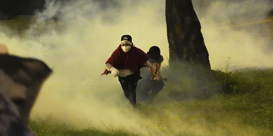 Indigene Demonstranten fliehen vor Tränengas, das von der Polizei eingesetzt wurde. Foto: Dolores Ochoa/AP/dpa