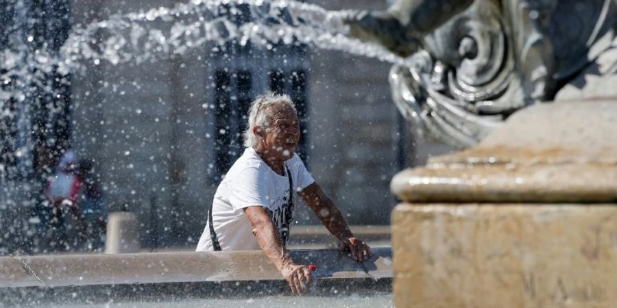 In Bordeaux erfrischt sich ein Mann an einem Brunnen