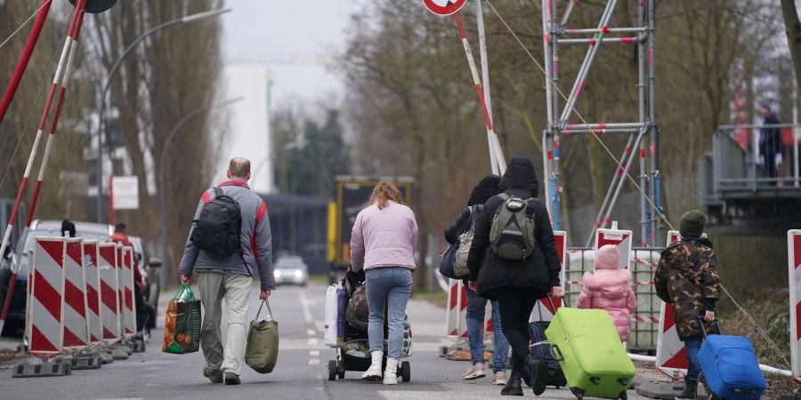 Aus der Ukraine geflüchtete Menschen verlassen mit ihrem Gepäck eine Unterkunft in Hamburg.