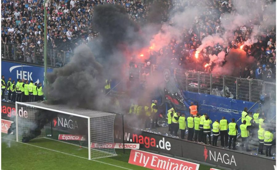 Trotz einem Sieg steigt der Hamburger SV ab und muss als letztes Bundesliga-Gründungsteam den Gang in die zweite Liga antreten. Unwürdig: Das Spiel muss unterbrochen werden, weil sich Chaoten daneben benehmen.