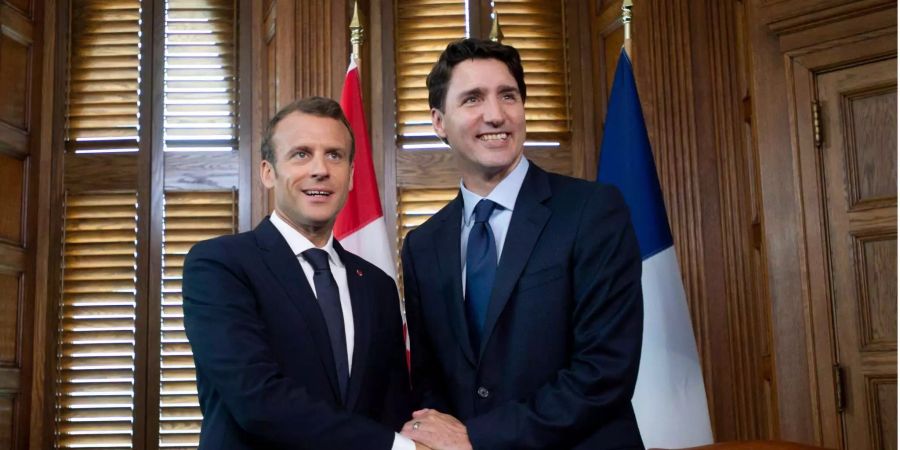 Emmanuel Macron (l), Präsident von Frankreich, schüttelt die Hand von Justin Trudeau, Premierminister von Kanada, in dessen Büro.