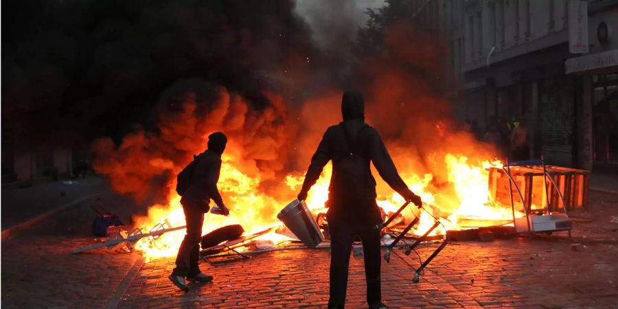 Randalierer stehen im Hamburger Schanzenviertel bei den Ausschreitungen rund um den G20-Gipfel vor einer brennenden Barrikade.