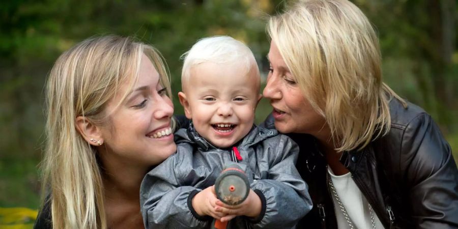 Albin (m.), das weltweit erst mithilfe einer Gebärmuttertransplantation geborene Kind, wird von seiner Mutter Emelie Eriksson (l.) und seiner Grossmutter Marie (r.) geherzt.