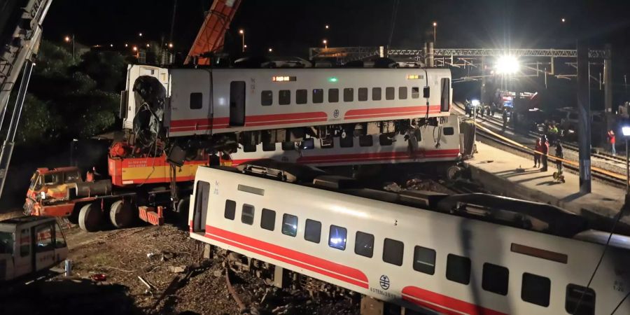 Rettungskräfte benutzen einen Kran um den entgleisten Zug in Taiwan zu entfernen.