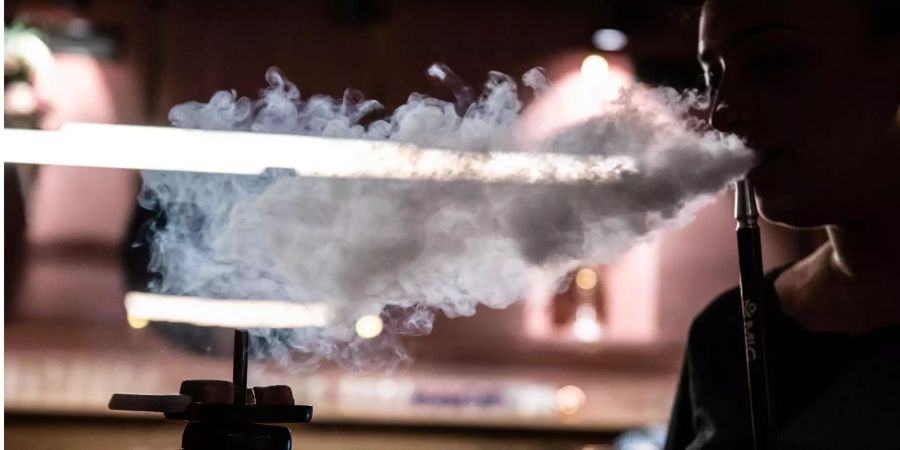 Eine junge Frau raucht in einer Shisha-Bar.