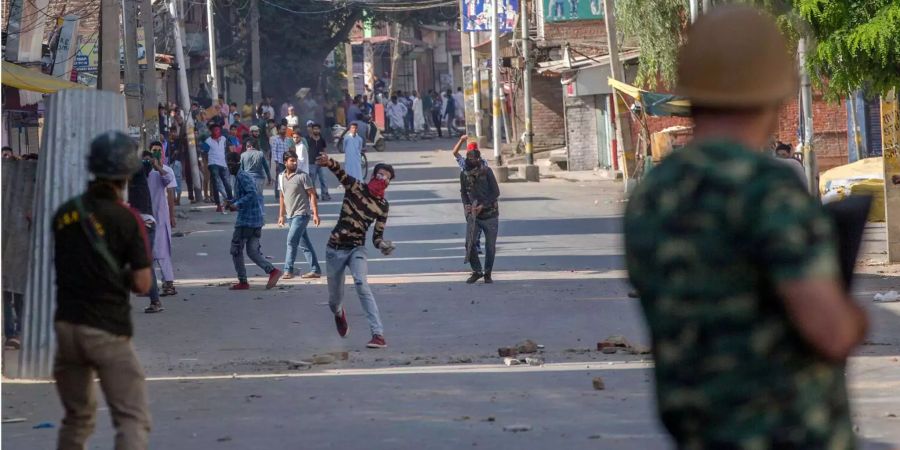 Indische Polizisten stehen während eines Protestes in Srinagar (IND) vor Demonstranten (Symbolbild).
