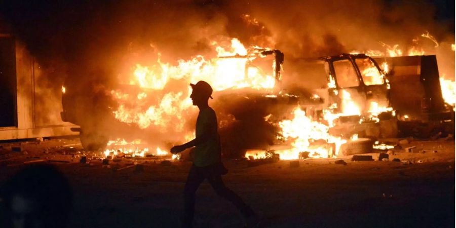 Ein Demonstrant läuft in Basra an einem brennenden Auto vorbei.