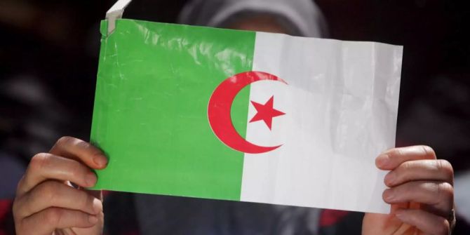 Eine Frau hält die Flagge von Algerien.