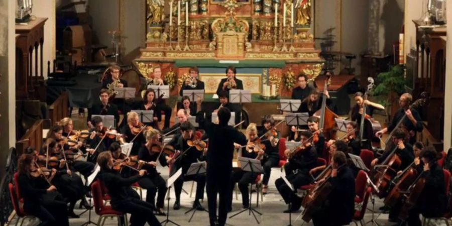 Ein Konzert von schweizerischen und deutschen Philharmonikern, bei denen die Frauen wie die Männer Hosen – keine Röcke – tragen.