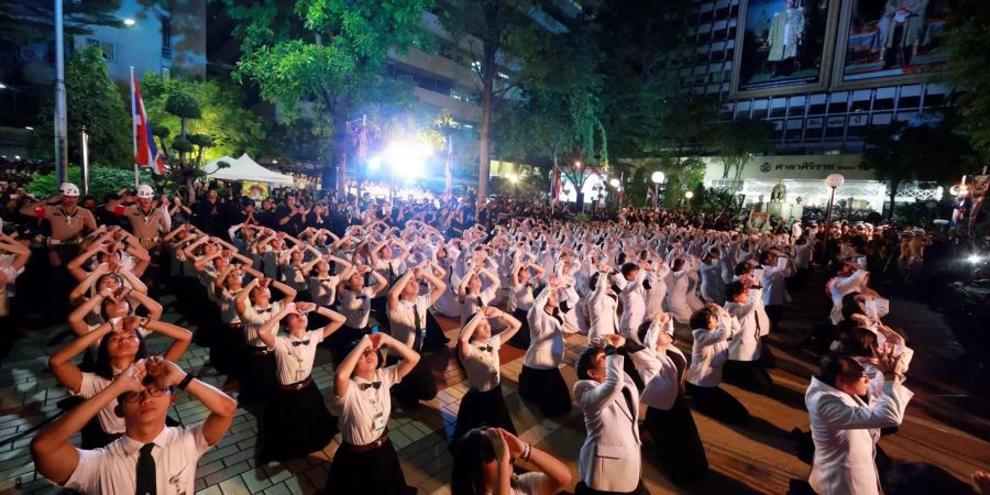 Trauernde verneigen sich in Bangkok neben Porträts des verstorbenen König Bhumibol.