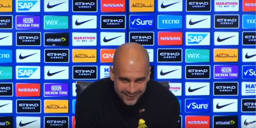 Pep Guardiola lacht an einer Pressekonferenz von Manchester City.