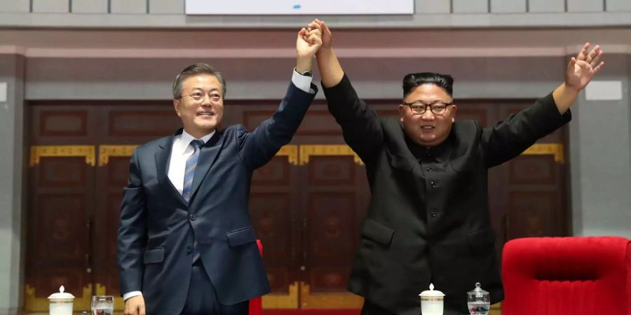 Südkoreas Präsident Moon Jae In und Nordkoreas Machthaber Kim Jong Un heben gemeinsam ihre Hand hoch.