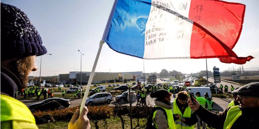 Demonstranten mit einer französischen Fahne blockieren eine Strasse, um gegen höhere Spritpreise zu demonstrieren. Im Land wächst die Sorge vor einem Verkehrskollaps.