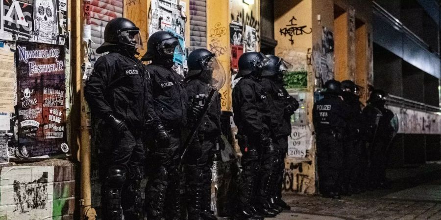 Polizeibeamte stehen bei einer Razzia in der Rigaer Strasse in Berlin-Friedrichshain vor einem Haus.