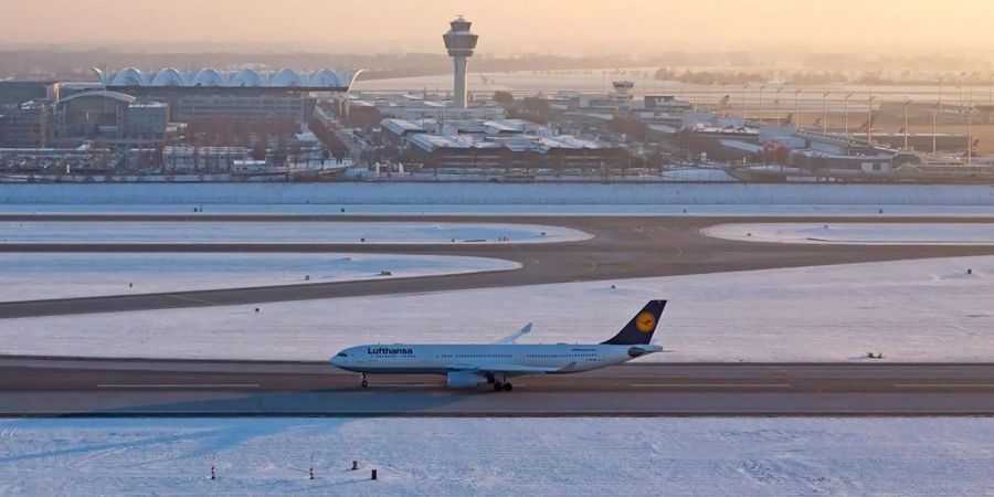 Eine Lufthansa-Maschine steht auf dem verschneiten Münchner Flughafen.