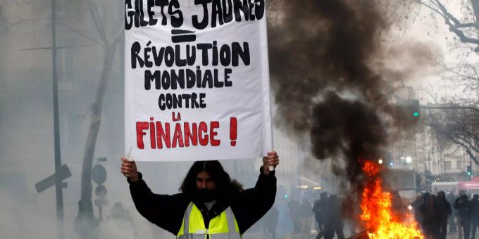 Ein Demonstrant hält ein Schild mit der Aufschrift «Gelbwesten = weltweite Revolution gegen die Finanzwirtschaft». Ein Demonstrant hält ein Schild mit der Aufschrift «Gelbwesten = weltw