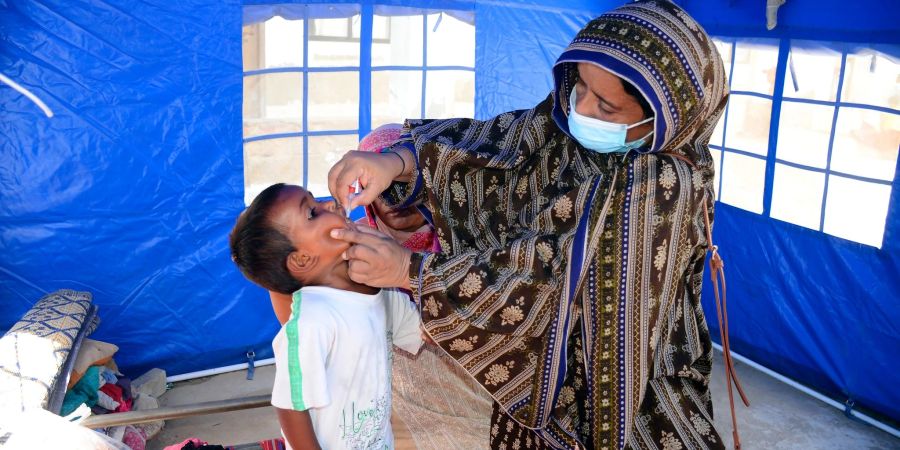 Nach den schweren Überschwemmungen in Pakistan verabreicht eine Mitarbeiterin des Gesundheitswesen einem Kind eine Schluckimpfung gegen Polio.