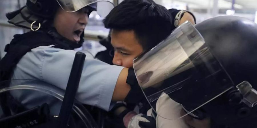 Polizisten in Schutzausrüstung nehmen einen Demonstranten im Hongkonger Flughafen fest. Kin Cheung/AP Foto: Kin Cheung