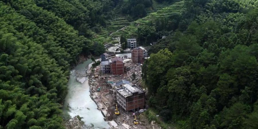 Nach einem Erdrutsch durch den Taifun «Lekima» sind Erdmassen und Wasser zwischen Häusern neben einem Waldgebiet zu sehen. Foto: Han Chuanhao/XinHua