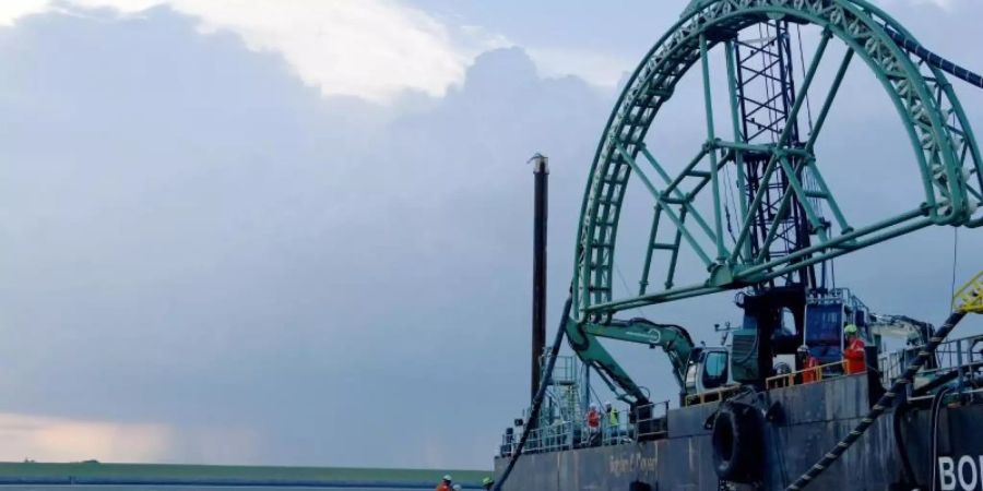 Das Endstück eines 516 Kilometer langen Seekabels wird vom Kabelverlegeschiff «Boka Connector» im Watt unter dem Deich hindurch an Land gezogen. Foto: Carsten Rehder