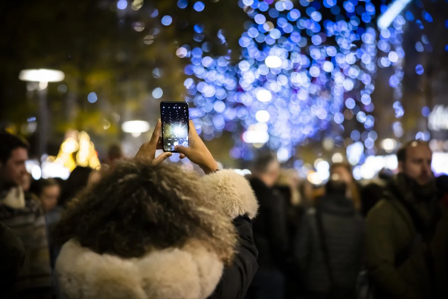 Menschen filmen mit ihrem Handy bei der Einschaltung der Weihnachtsbeleuchtung in Zürich im November 2022.