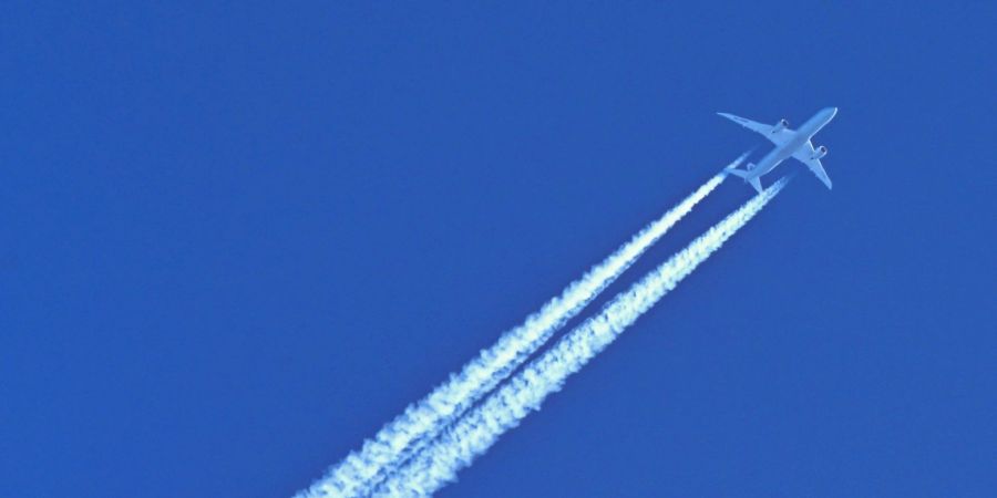 Schönes Motiv aber schlecht für Umwelt und Klima: Ein Flugzeug hinterlässt am blauen Himmel Kondensstreifen.