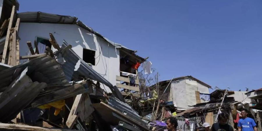 Bewohner suchen in den zerstörten Häusern nach Habseligkeiten. Foto: Jay Labra/AP/dpa