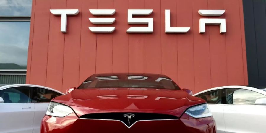 Tesla-Autos vor Firmenlogo