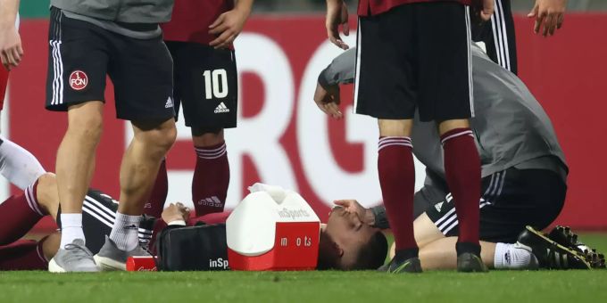 Der Nürnberger Tom Krauss (u) liegt verletzt auf dem Rasen. Betreuer und Teammitglieder kümmern sich um ihn. DFB-Pokal