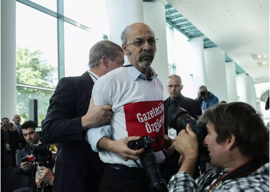 Ertugrul Yigit, Chefredakteur des Internetportals Aurupa Postasi, der ein T-Shirt mit der Aufschrift "Pressefreiheit für Journalisten in der Türkei" trägt, wird im Bundeskanzleramt aus der gemeinsamen Pressekonferenz von Bundeskanzlerin Merkel und Erdogan, Präsident der Türkei geführt.