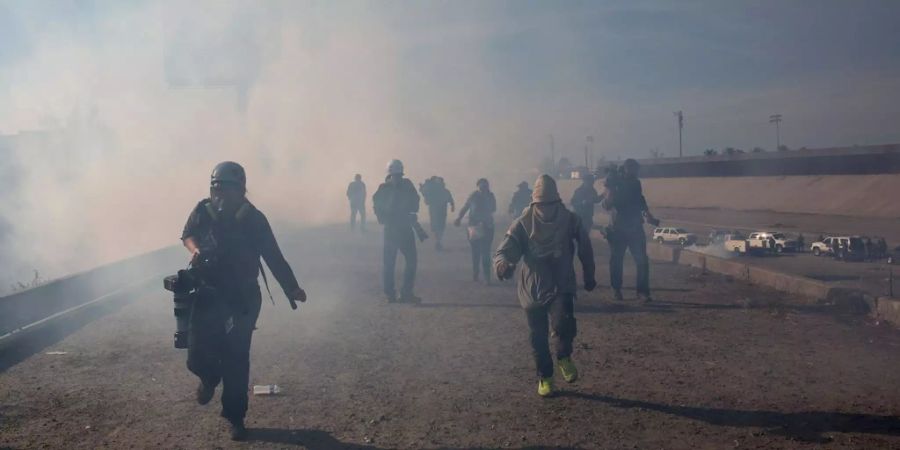 Flüchtlinge und Reporter bringen sich vor Tränengas in Tijuana in Sicherheit.