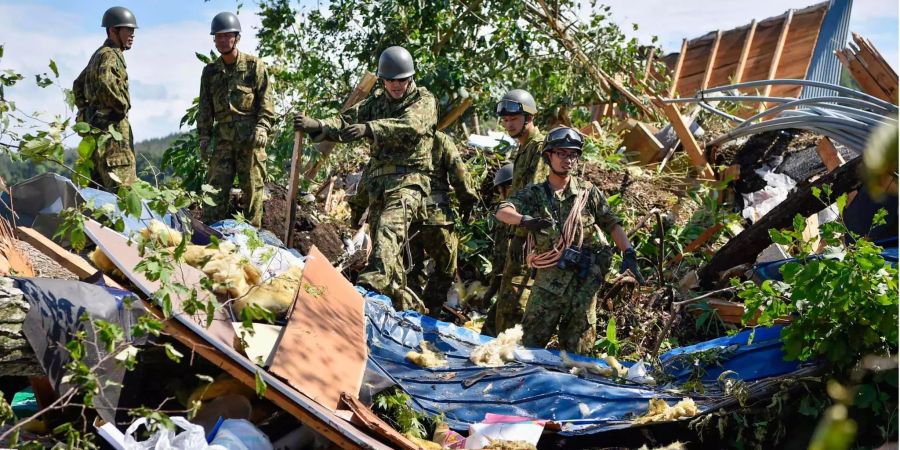 Rettungskräfte suchen auf der japanischen Insel Hokkaido nach vermissten Einwohnern in der Nähe von Gebäuden, die durch einen Erdrutsch zerstört wurden.