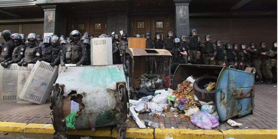 Polizisten stehen vor der Generalstaatsanwaltschaft in Kiew während einer Protestaktion von Aktivisten, die dort u. a. Müllcontainer ausgeleert haben.