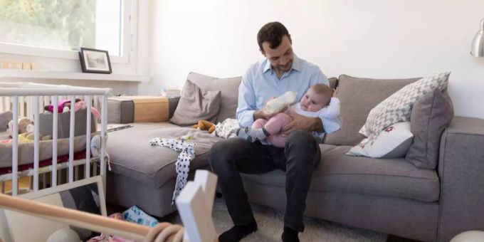 Zwei Drittel aller Väter haben heute keinen Anspruch auf bezahlten Vaterschaftsurlaub: ein Mann gibt seiner Tochter die Flasche Zwei Drittel aller Väter haben heute keinen Anspruch auf bezahlten Vaterschaftsurlaub: ein Mann gibt seiner Tochter die Flasche