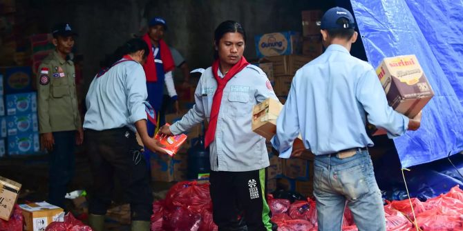 Helfer verteilen Lebensmittel in einer Notunterkunft in Indonesien.