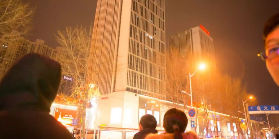 Leute schauen auf den Wanda Plaza in Changchun nach Explosionen.